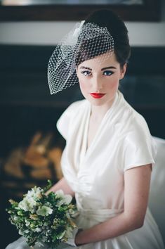 a woman in a white dress and veil holding a flower bouquet with her right hand