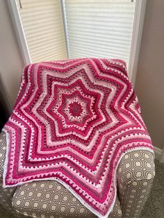 a crocheted blanket sitting on top of a chair in front of a window