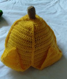 a crocheted yellow hat with a brown top on a white surface next to other items