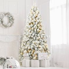 a white christmas tree with presents in front of it