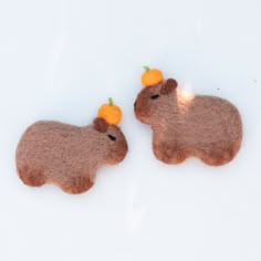 two felt animals with oranges on their heads, one brown and the other tan