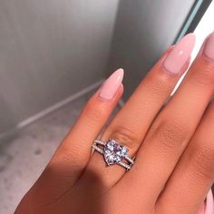 a woman's hand with two engagement rings on her fingers, and the ring has a diamond in it