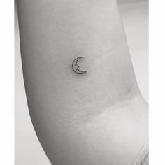 a small crescent moon tattoo on the side of a woman's right arm,