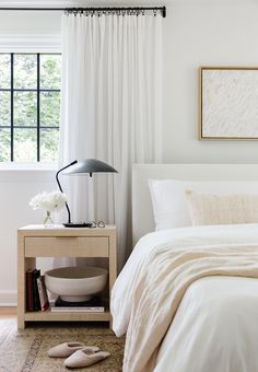 a bedroom with white bedding and curtains