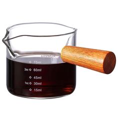 a glass measuring cup filled with liquid next to a wooden spoon