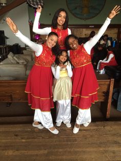 three women in red and white outfits posing for a photo with their arms up while one woman holds her hat above her head