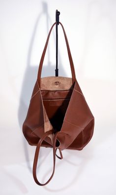 A lightweight and spacious Leather Shopper Bag-Tan you can use for your office, gym and after-hours essentials while still looking stylish. Handmade from supple calfskin Italian leather, the versatile look features over-the-shoulder handles and minimal detailing. Raw edges and no lining makes this style super light and easy to fold when traveling. Inside is a zippered document pouch and a leather cell phone pouch. Details: Color: TanTwo leather strap for closing the bag.Natural unlined interiorM Brown Leather Tote Bag, Leather Shopper Bag, Cell Phone Pouch, Office Gym, Bespoke Gifts, Brown Leather Bag, Personalized Accessories, Phone Pouch, Black Leather Bags