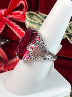 Simulated Ruby Ring Description Intaglio Design#31 MADE TO ORDER Inspired by the intricate Victorian designs of the late 1800s, I now offer this gorgeous filigree Antique reproduction in sterling silver. The lovely ring is set with a flawless 7ct simulated red ruby. The baguette rectangle-cut red ruby color gem is 18mm long by 9mm wide. The ring is 8mm off the finger. The inside of the band is marked 925 for sterling. Notice the intricate and detailed design of the silver filigree setting and ba Oval Ruby Ring With Intricate Design, Intricate Ruby Wedding Ring, Red Jewelry With Accent Stones For Formal Occasions, Red Ruby Filigree Ring For Wedding, Red Victorian Filigree Ring For Anniversary, Formal Heirloom Ruby Ring, Red Vintage Filigree Ring With Gemstone, Fine Jewelry Red Ruby Ring With Intricate Design, Red Ruby Filigree Ring Gift