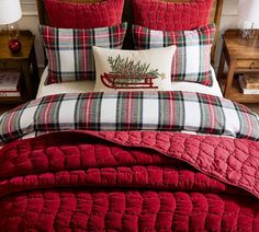 a red bed with plaid comforter and pillows