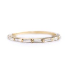 a thin gold band with three baguettes on the side, set in 18k yellow gold