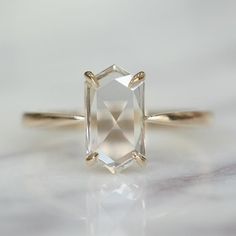 an engagement ring with a large white diamond in the center, on a marble surface