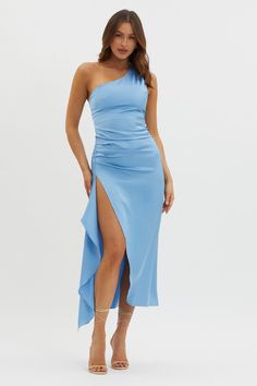 a woman wearing a blue one shoulder dress with high slit and side split, standing in front of a white background