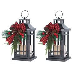 two metal lanterns with christmas decorations and pine cones