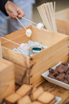 a wooden box filled with marshmallows on top of a table next to other foods