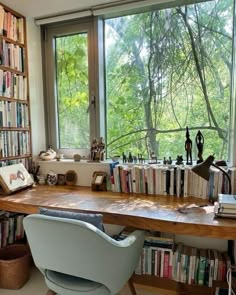 a chair sitting in front of a window filled with lots of books on top of a wooden table