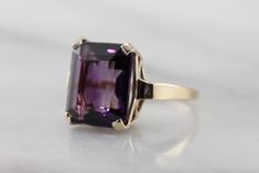 Classic elegance! We've completely restored this vintage, yellow gold mounting and set it with a gorgeous new amethyst of the deepest shade of aubergine purple! The bold but simple style of this ring allow it to be worn for a variety of occasions, from a day to day signature piece to an eye-catching accessory for the finest gown. Metal: 14K Yellow Gold Gem: Amethyst 9.55 Carats Gem Measurements: 13.9 x 11.9 mm, Rectangle Emerald Cut Ring Size: 7.25 Marks: "JAM14K" Stamped on the inside band Classic Purple Amethyst Ring, Elegant Purple Ring With Polished Finish, Elegant Purple Rings With Polished Finish, Purple Amethyst Ring For Anniversary, Timeless Formal Amethyst Ring, Vintage Purple Amethyst Ring With Polished Finish, Classic Amethyst Purple Rings, Classic 14k Gold Purple Amethyst Ring, Formal Purple Amethyst Ring In 14k Gold