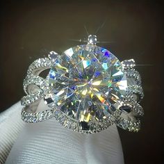 a diamond ring is sitting on top of a white cloth with an intricate design around it