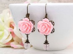 "These are romantic vintage inspired light pink rose earrings. They feature beautiful pink resin roses on top of brass floral filigrees and paired with natural rose quartz beads. They hang underneath leverback earrings. The earrings measure about 56mm (2.2 inches) from the top of the ear wire to the bottom of the pearl. They are perfect for occasions, a wonderful idea for gift giving and as a little treat for yourself. Your earrings will presented in a gift box and tied with ribbon. Measurements Vintage Rose Gold Flower Earrings For Wedding, Pink Rose Design Flower Earrings For Valentine's Day, Feminine Pink Jewelry With Rose Design, Pink Rose Design Jewelry For Wedding, Pink Flower Earrings For Wedding On Valentine's Day, Pink Flower Earrings For Wedding And Valentine's Day, Charming Pink Jewelry For Wedding, Charming Pink Wedding Jewelry, Pink Rose Design Earrings For Valentine's Day