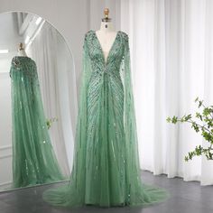 a green dress is on display in front of a mirror and vase with greenery