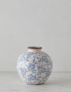 a blue and white vase sitting on top of a marble counter next to a wall