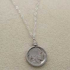 Introducing our exquisite Buffalo/Indian Head Nickel Necklace, a must-have accessory for history buffs, coin collectors, and vintage coin enthusiasts. This timeless piece effortlessly complements both casual and formal wear, making it a versatile addition to your jewelry collection. Featuring an authentic antique Buffalo Nickel from the early 1900s, each necklace tells a unique story of the past. Choose between our sophisticated 18-inch black cord or our elegant 20-inch silver plated braided rope chain, allowing you to customize the necklace to your personal style. Rest assured, every coin used in our necklaces is carefully cleaned before assembly, retaining the coin's original authenticity while enhancing its visual appeal. The bezel mount not only adds a touch of elegance but also serves Collectible Round Coin Pendant Jewelry, Antique Coin Jewelry For Vintage Collection, Antique Round Jewelry For Commemoration, Antique Coin Jewelry From Vintage Collection, Antique Commemorative Round Jewelry, Vintage Jewelry With Coin Pendant For Collectors, Antique Medallion Jewelry For Commemoration, Vintage Collectible Jewelry With Coin Pendant, Heirloom Coin Pendant Collectible Jewelry