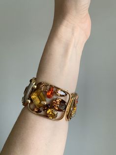 "Vintage 1940's statement signed Napier bracelet. Gold tone bracelet with amber, brown, and bright orange rhinestone crystals. Rhinestones are oval, circle, baguette, emerald, and tear drop cut. Bracelet in excellent condition with minor wear due to age. High quality and high shine rhinestones. Measurements Length: 6-3/4\" / Width: 1-1/2\" / Unless otherwise stated all vintage items are used and may have minor to moderate wear or discoloration considering the age of the item. Most items have bee Multi-stone Metal Jewelry For Party, Retro Metal Jewelry, Vintage Amber Jewelry For Party, Brown Bangle Jewelry For Formal Occasions, Vintage Jeweled Bracelets For Collectible, Vintage Brown Bracelets For Party, Unique Jeweled Bracelets For Formal Occasions, Brown Bangle For Formal Occasions, Vintage Jeweled Cuff Bracelet For Formal Occasions