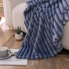 a blue blanket sitting on top of a wooden floor next to a cup and saucer