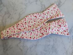 Upgrade your wardrobe in style with this stunning white and pink coloured floral bow tie. Perfect gift for him, this unique fully adjustable bow tie will elevate any occasion including weddings, birthdays and anniversaries. Made from cotton. Pink Floral Bow Tie, Classic White Bow As Gift, White Spring Party Bow Tie, Adjustable White Bow Tie With Decorative Bow, White Adjustable Bow With Butterfly Knot, White Bow Tie For Spring, White Bow With Tie Back For Spring, White Bow Tie Gift, White Bow Tie For Gifts