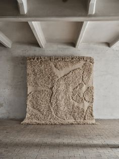 a large stone sculpture sitting on top of a brick floor next to a white wall