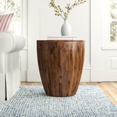 a wooden table sitting on top of a blue rug next to a white couch in a living room