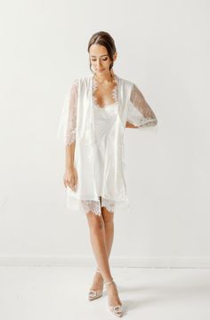 Made in a unique delicate white french lace design, the Lara Lace Robe is the perfect gift for the bride-to-be on her wedding day. Featuring scalloped lace edges along the neckline, hem and sleeve cuffs, this robe exudes old-world elegance. The body of the Lara Robe is fully lined to provide our brides the coverage they need. A slip dress is not required for under this robe, but if you're in search of one we recommend our 'Date Night' Slip Dress. Material: French lace with body liningSleeve: 3/4 White Lace Bridesmaid Dress With Scalloped Lace, Lace Dress With Lace Cuffs For Wedding Night, White Scalloped Lace Dress For Bridesmaid, Elegant Lace Dress With Scalloped Lace For Wedding Night, Elegant Lace Dress With Lace Trim For Wedding Night, Elegant Scalloped Lace Dress For Wedding Night, Lace Wedding Dress With Lace Cuffs, White Lace Dress With Lace Bodice For Ceremonies, White Lace Dress With Lace Sleeves For Bridesmaid