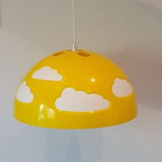 a yellow lamp hanging from a ceiling with clouds painted on the lampshade above it