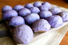 a wooden cutting board topped with purple doughnuts