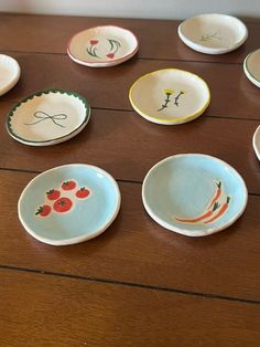 many small plates with designs on them sitting on a wooden table next to each other