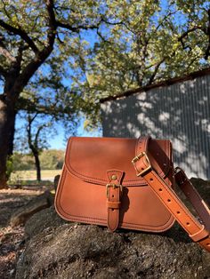 The Marlondo Leather Saddle Crossbody Purse is a vintage inspired saddle bag purse, perfect for weekend adventures and everyday carry. This purse has a belted buckle closure for a timeless chic look. The Saddle Crossbody features an interior pocket and two slot pockets on the bag's exterior: one across the rear of the bag and another just under the main flap. The Saddle Crossbody also comes with an adjustable and removable strap. The Marlondo Leather Crossbody is made with beautiful full grain v Vintage Brown Belt Bag For Everyday Use, Everyday Saddle Bag With Detachable Strap, Cognac Satchel Shoulder Bag With Brass Hardware, Vintage Leather Belt Bag For Travel, Cognac Saddle Bag With Removable Pouch, Classic Saddle Flap Bag For Everyday Use, Everyday Saddle Bags With Brass Hardware, Brown Saddle Bag With Brass Hardware, Cognac Saddle Bag With Detachable Strap For Travel