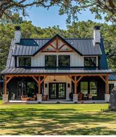 a large house with a metal roof in the middle of a grassy area surrounded by trees