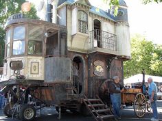 an old fashioned horse drawn carriage in front of a building with people standing around it