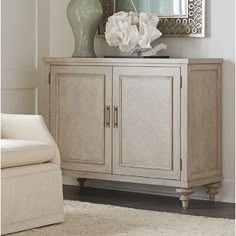 a white cabinet with a mirror and vase on top of it in a living room