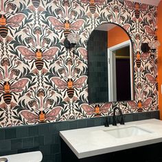 a bathroom with a sink, mirror and wallpaper in the shape of honeybees