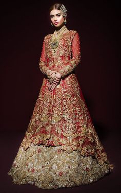 a woman in a red and gold bridal gown, standing against a dark background