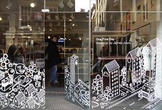 the reflection of people walking in and out of a store window with black and white designs on it