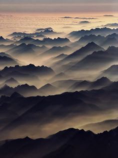 an aerial view of mountains and valleys at sunset