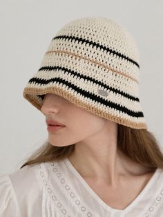 a woman wearing a crocheted hat with black and white stripes on the brim