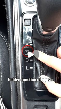 a person is pressing the button on a car's gear selector with their finger