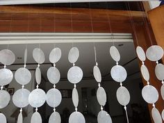 a group of white plates hanging from the ceiling in front of a window with wood trim