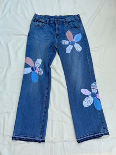 a pair of jeans with flowers painted on them sitting on top of a white sheet