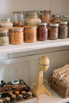 an assortment of spices and other items on a shelf in a kitchen with white walls