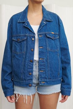 A crisp and clean dark wash jacket from Rustler - elevate any outfit. Lightweight denim so perfect for fall and beyond. Features no distressing, front chest pockets and front lower pockets. 100% Cotton. Listed size XL (Women’s). Fits like Large. Model is size S and 5’6”. - Shoulders: 20” - Chest: 25” - Length: 24” - Sleeve: 25.5” Classic Medium Wash Outerwear For Everyday, Classic Medium Wash Everyday Outerwear, Classic Everyday Outerwear In Medium Wash, Classic Dark Wash Outerwear For Everyday, Classic Denim Blue Outerwear For Everyday, Classic Medium Wash Denim Outerwear, Classic Denim Outerwear In Medium Wash, Classic Medium Wash Denim Jacket, Classic Medium Wash Denim Jacket For Everyday