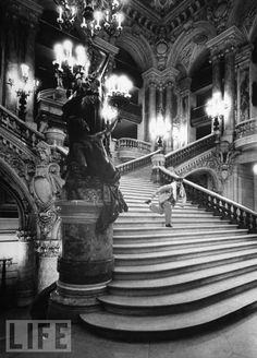 an old black and white photo of a staircase in a building with chandeliers hanging from the ceiling