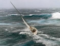 a sailboat in the middle of choppy ocean water with large waves behind it